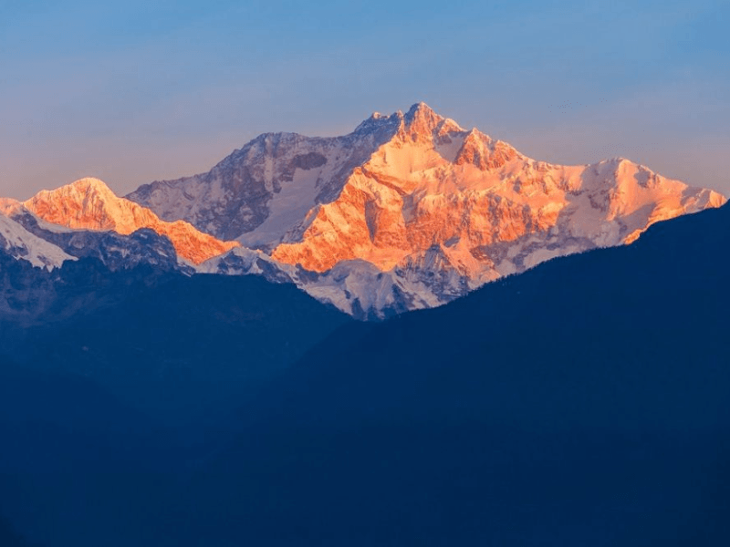 Golden sunrise light on the Kanchenjunga massif over blue Himalayan ridgelines in eastern Nepal